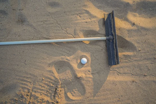 Golf konsepti. Golf topu ve tırmık kum sığınakta güzel golf sahasında gün batımında arka planda.                               