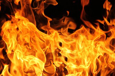 Siyah arka planda yangın alevleri. Doğal ormandaki yangın, alevler ve kıvılcımlar arka planda karanlık bir yakıt, siyah bir arka planda ışıklar.