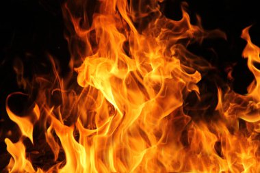 Siyah arka planda yangın alevleri. Doğal ormandaki yangın, alevler ve kıvılcımlar arka planda karanlık bir yakıt, siyah bir arka planda ışıklar.