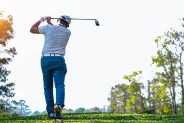 Akşam golf sahasında golf oynayan bir golfçü. Güneşin altında golf oynayan bir adam..                                   