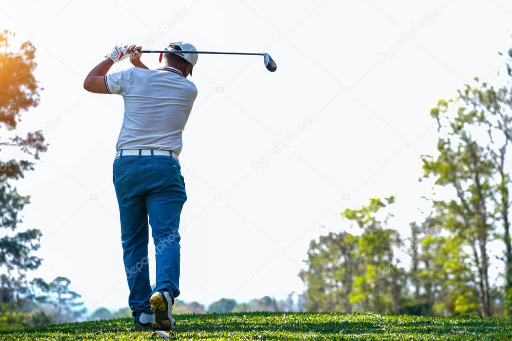 Golfer playing golf in the evening golf course, on sun set evening time. Man playing golf on a golf course in the sun.                                   