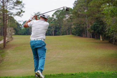 Akşam golf sahasında golf oynayan bir golfçü. Güneşin altında golf oynayan bir adam..                                 