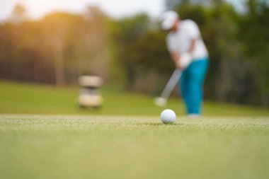 Golf topları gün batımında golf sahasında golf oyuncuları tarafından delik deşik edilecek. Golfçüler akşam saatlerinde golf sahasına golf oynuyorlar..                               