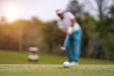 Golf topları gün batımında golf sahasında golf oyuncuları tarafından delik deşik edilecek. Golfçüler akşam saatlerinde golf sahasına golf oynuyorlar..                                  