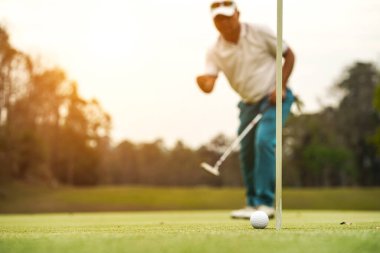 Golf topları gün batımında golf sahasında golf oyuncuları tarafından delik deşik edilecek. Golfçüler akşam saatlerinde golf sahasına golf oynuyorlar..                                  