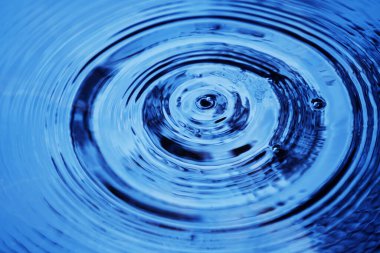 Yağmur damlaları suyun pürüzsüz yüzeyine düşer. Su damlacıkları yüzeyi etkiler ve yüzeyde halkalar oluştururlar..                               