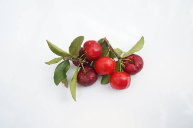 Taze acerola meyvesi, tipik Brezilyalı. Beyaz zemin üzerinde yarım dilimli ve yeşil yapraklı kırmızı organik Acerola kirazı, yüksek vitamin C ve antioksidan meyveler.                                 