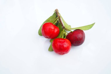 Taze acerola meyvesi, tipik Brezilyalı. Beyaz zemin üzerinde yarım dilimli ve yeşil yapraklı kırmızı organik Acerola kirazı, yüksek vitamin C ve antioksidan meyveler.                                