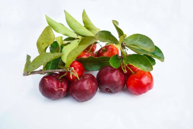 Taze acerola meyvesi, tipik Brezilyalı. Beyaz zemin üzerinde yarım dilimli ve yeşil yapraklı kırmızı organik Acerola kirazı, yüksek vitamin C ve antioksidan meyveler.                                 
