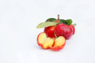 Taze acerola meyvesi, tipik Brezilyalı. Beyaz zemin üzerinde yarım dilimli ve yeşil yapraklı kırmızı organik Acerola kirazı, yüksek vitamin C ve antioksidan meyveler.                               