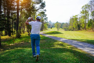 Akşam golf sahasında golf oynayan bir golfçü. Güneşin altında golf oynayan bir adam..                               
