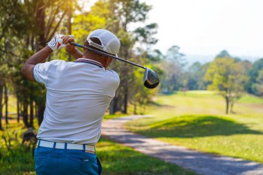 Akşam golf sahasında golf oynayan bir golfçü. Güneşin altında golf oynayan bir adam..                               