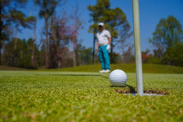 Golf topları gün batımında golf sahasında golf oyuncuları tarafından delik deşik edilecek. Golfçüler akşam saatlerinde golf sahasına golf oynuyorlar..                               