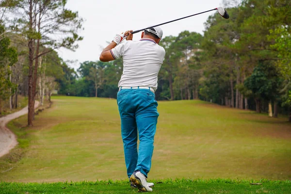 Akşam golf sahasında golf oynayan bir golfçü. Güneşin altında golf oynayan bir adam..                             