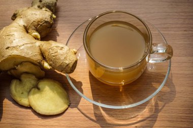 Sıcak zencefil suyu ve ahşap bir masanın üzerinde sabah güneşinin altında zencefil suyu vücut ısısını arttırır..                               