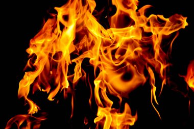 Siyah arka planda yangın alevleri. Doğal ormandaki yangın, alevler ve kıvılcımlar arka planda karanlık bir yakıt, siyah bir arka planda ışıklar.