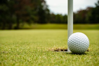 Yeşil sahadaki golf topunun en üst görüntüsü. Golf topu ve golf sopası akşam golf sahasında güneş ışığı altında..                                 