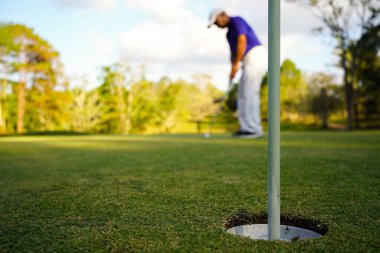 Bulanık golfçü akşam vakti golf sahasında golf oynuyor. Güneşin altında golf oynayan bir adam..                                   
