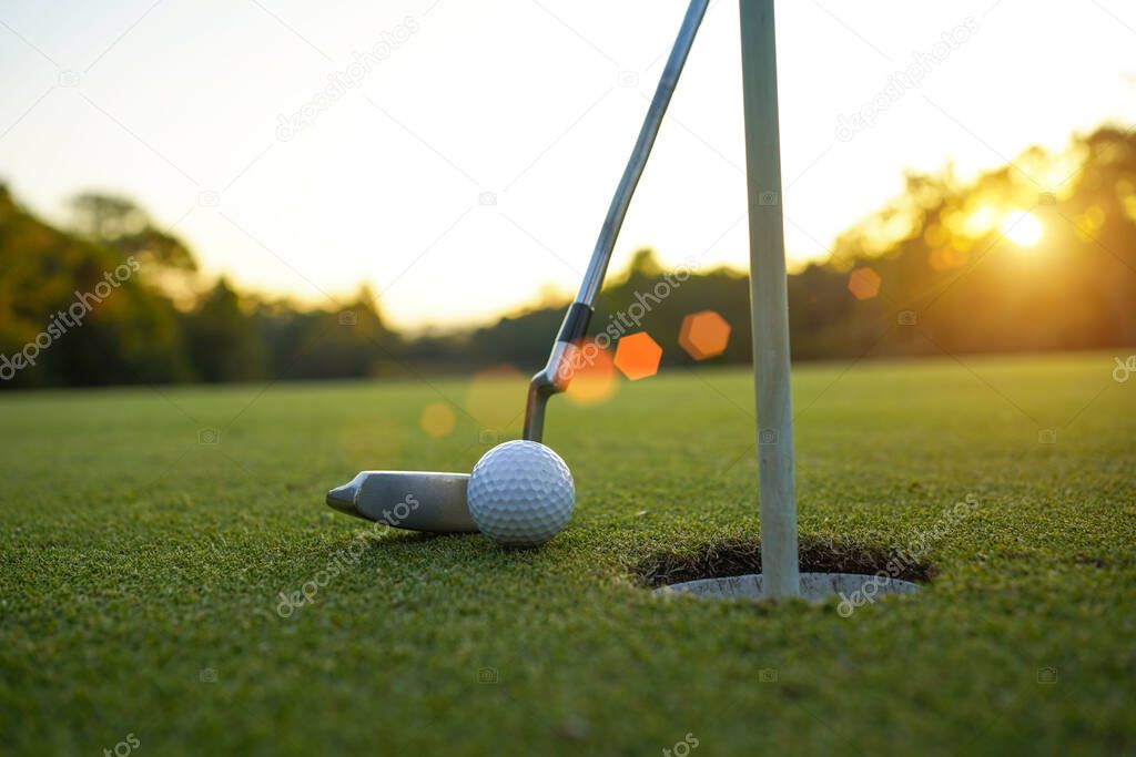 Golf clubs and ball on a green lawn in a beautiful golf course with morning sunshine. golf ball on green grass ready to hit on golf course background.                                