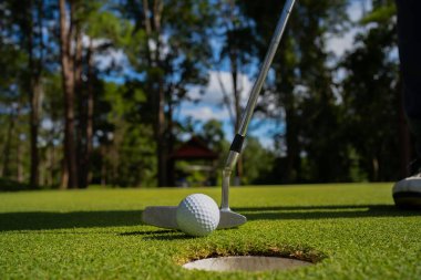 Golfçü topu yeşil golfün üstüne koyuyor, mercek akşam vakti parlıyor. Bulanık golfçü akşam golf sahasında güneş ışığıyla golf oynuyor.. 