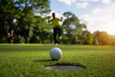 Golfçü topu yeşil golfün üstüne koyuyor, mercek akşam vakti parlıyor. Bulanık golfçü akşam golf sahasında güneş ışığıyla golf oynuyor.. 