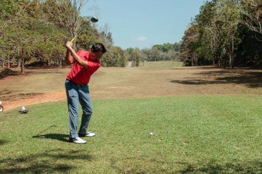 Golfçü golf oynuyor ve yeşil çimen dağ arka planına vuruyor. Asya 'lı erkek oyuncu yazın vuruldu. Spor tatil yaşam tarzı konsepti.