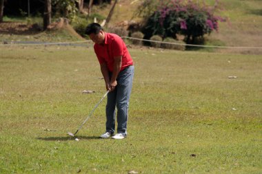 Golfçü golf oynuyor ve yeşil çimen dağ arka planına vuruyor. Asya 'lı erkek oyuncu yazın vuruldu. Spor tatil yaşam tarzı konsepti.