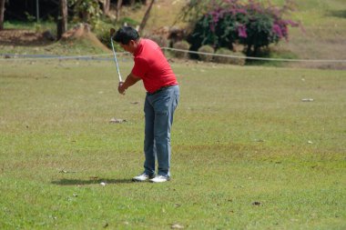 Golfçü golf oynuyor ve yeşil çimen dağ arka planına vuruyor. Asya 'lı erkek oyuncu yazın vuruldu. Spor tatil yaşam tarzı konsepti.
