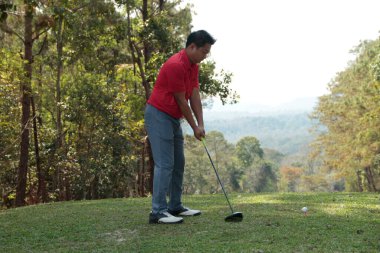 Golfçü golf oynuyor ve yeşil çimen dağ arka planına vuruyor. Asya 'lı erkek oyuncu yazın vuruldu. Spor tatil yaşam tarzı konsepti.