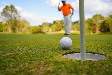 Golfçü topu yeşil golfün üstüne koyuyor, mercek akşam vakti parlıyor. Bulanık golfçü golf sahasında golf oynuyor..                               