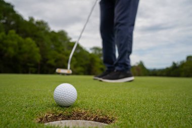 Golfçü topu yeşil golfün üstüne koyuyor, mercek akşam vakti parlıyor. Bulanık golfçü golf sahasında golf oynuyor..