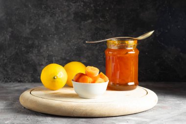 Cam kavanozda tatlı havuç reçeli, doğranmış havuç ve iki sulu sarı limon.