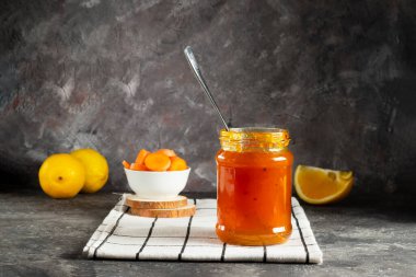 Tatlı havuç reçeli cam kavanozda doğranmış havuçla birlikte limonlu ve sulu portakal dilimli beyaz bir peçete.