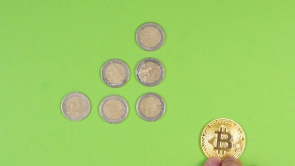 若い成功した男性投資家やトレーダーの手は 緑の背景に他のコインの成長を背景に金ビットコインを動かす — ストック動画