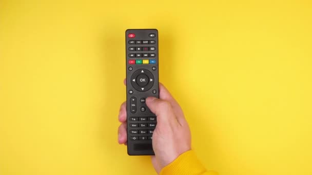 Male Hand Presses Buttons Black Remote Control Smart Yellow Background — Stock Video