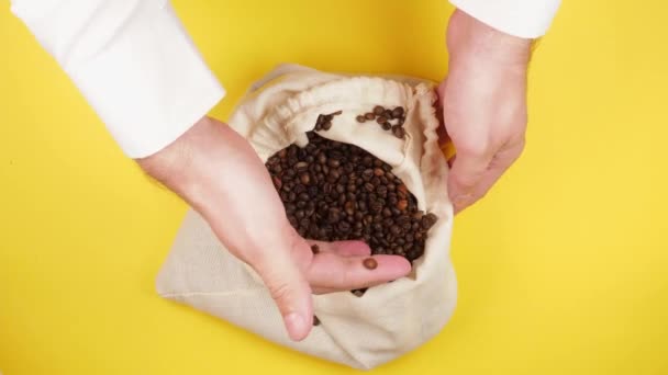 男人的手穿着白衬衫 从黄底的环保麻袋中取出香喷喷的咖啡豆 — 图库视频影像