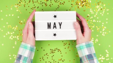 Ekose gömlekli genç bir kızın elleri üzerinde yeşil bir arkaplan ve parlak yıldızlar olan beyaz bir tahta tutuyor.