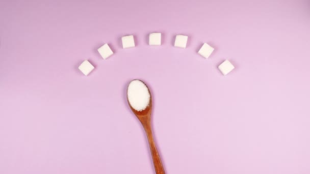 白糖方块和木制生态勺子在粉红背景下制成的糖尿病血糖秤 — 图库视频影像
