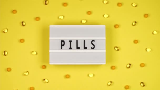 Nápis Pilulky Bílém Prkně Žlutém Pozadí Spoustou Pilulek Vitamínů Pro — Stock video