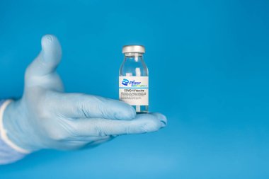 İzmir, Türkiye - 17 Ocak 2021: Coronavirus aşısı kavramı ve geçmişi. Yeni aşı pfizer ve biyoteknoloji mavi arka planda izole edildi. Covid-19, 2019-nCov salgını.