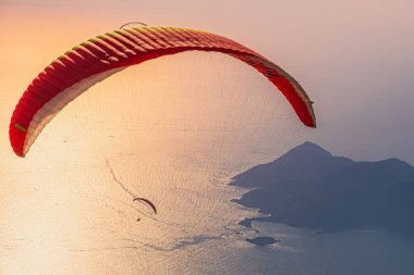 Gün batımında Fethiye 'deki Oludeniz plajında paraglider uçuyor. Mugla, hindi. Seyahat güzergahı. Yaz ve tatil konsepti.