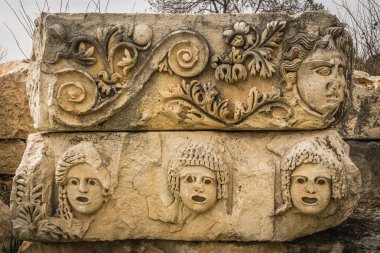 Çiçek süsleri ve yüzleri, Demre, Antalya, Türkiye 'de bulunan levrek kabartmaları korunmuş. Tiyatro maskeleri.