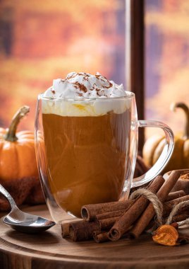 Balkabağı aromalı latte. Sonbahar arkaplanı olan bir pencere kenarında tarçın çubukları ve kabak kabakları.