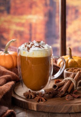 Balkabağı aromalı latte. Sonbahar arkaplanı olan bir pencere kenarında tarçın çubukları ve kabak kabakları.