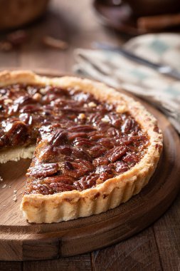 Dilimlenmiş pekan cevizli turtanın ahşap bir tabakta yakın çekimi.