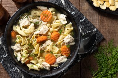 Havuçlu ve ahşap bir masada dereotlu tavuk çorbası.