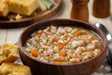 Ahşap bir masada mısır ekmeği ve havuç ve soğanlı jambon çorbası. Yakın plan.