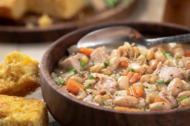 Ahşap bir masada mısır ekmeği ve havuç ve soğanlı jambon çorbası. Yakın plan.