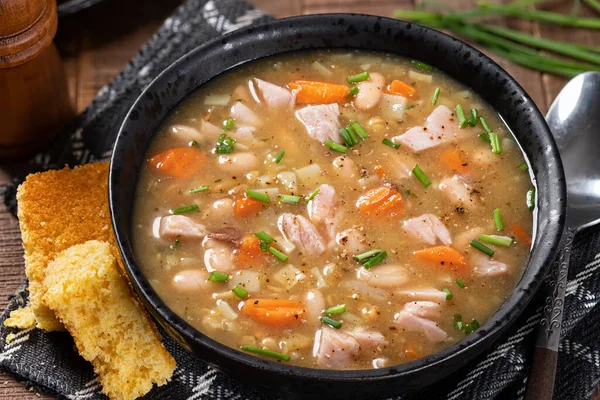 Closeup Ham Bonensoep Een Zwarte Kom Met Maïsbrood — Stockfoto