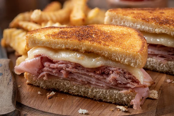 Kızarmış jambonlu ve peynirli sandviçin, tahtadan yapılmış patates kızartmasıyla ikiye bölünmüş hali.